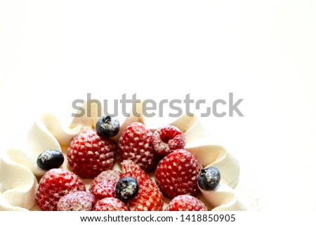 White cake decorated with strawberries and blueberries placed on a tray on a white table. close up.