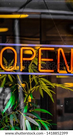 Panorama Close up of a neon open sign hanging on the glass wall of a commercial building