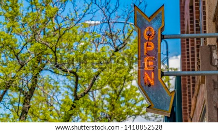 Panorama frame Open arrow sign on a building with vibrant trees and blue sky in the background
