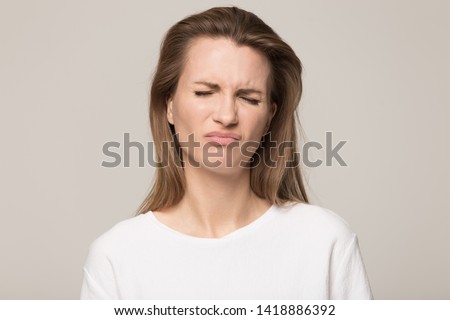 Portrait unhappy young woman with closed eyes and pout lips feeling upset, emotional sad attractive young female, funny childish face expression, reaction, close up isolated on studio background Royalty-Free Stock Photo #1418886392