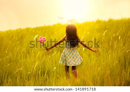 Little girl running on meadow with sunset