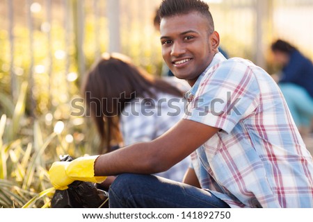 handsome teen volunteer cleaning streets with friends Royalty-Free Stock Photo #141892750