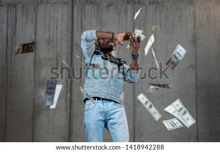 business, people and finances concept  Happy young african american businessman throwing US dollar banknotes and enjoying while making the rain of money in new startup office