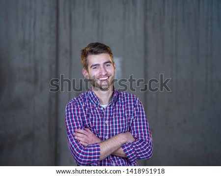 portrait of young successful smiling casual businessman standing in front of a concrete wall at new startup office