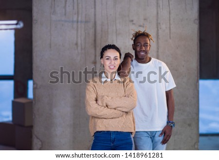 portrait of young multiethnic successful casual business team standing in front of a concrete wall at new startup office