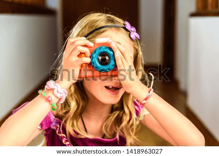 Little girl playing with a colorful photo camera toy made of wood.