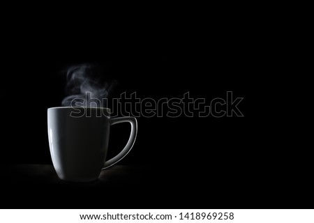 White coffee cup and smoke vapor.On a black wooden table.Dark tone.Space for text. Royalty-Free Stock Photo #1418969258
