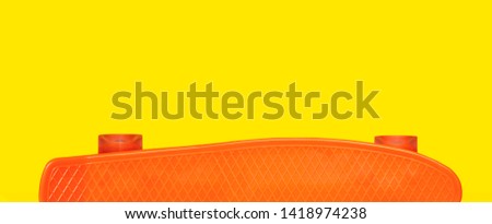 Design poster for sports. Orange plastic mini cruiser board on yellow background. skateboard with copy space. Banner for recreation, leisure, sport equipment.