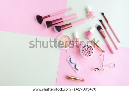 Makeup products, decorative cosmetics on pastel color pink mint background  flat lay.  Fashion and beauty concept. Top view. Copy space.