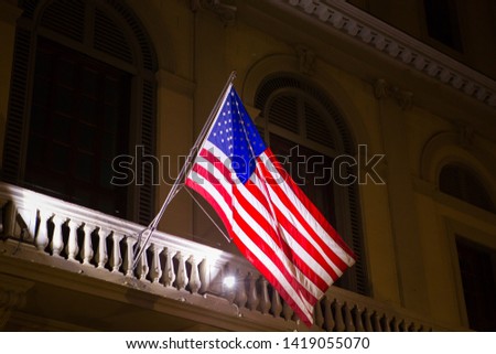 United States of America flag in the night illumination on the background of the facade of the building