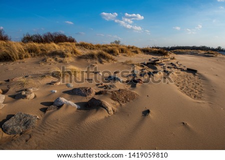 windy sea beach with white sand and blue water and dramatic clouds in the sky