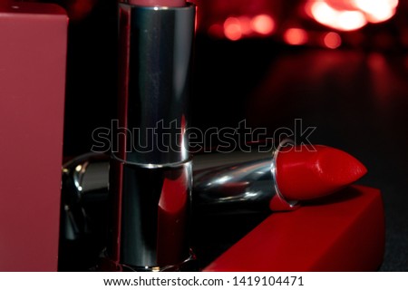red and beige lipstick, dark background, close up photo