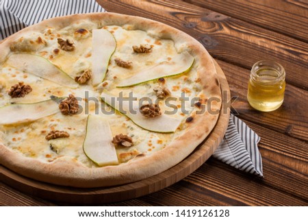 Traditional pizza with pear, nuts and blue cheese on a wooden background. Close up. Top view. Pear pizza on wooden board on a light background. Top view