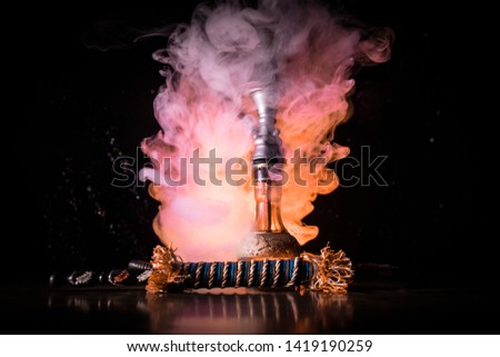 Hookah hot coals on shisha bowl on dark foggy background. Stylish oriental shisha. Creative concept
