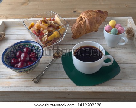 Breakfast.Fruit salad.Black coffee and croissant.On a wooden tray.