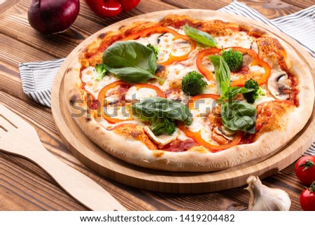 Vegetarian pizza on a wooden background with mushrooms, broccoli, cheese and sweet pepper and basil. 