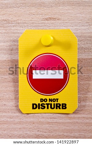 Do not disturb label with a thumbtack on a wooden background/Do not disturb label