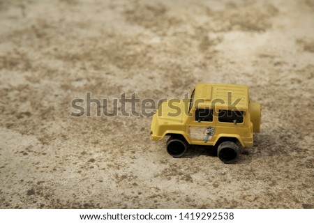Old yellow car toy on concrete.