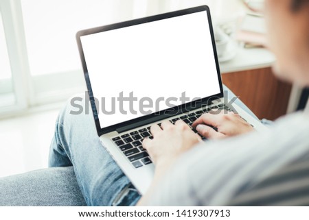 mockup image computer screen with blank space for text,sitting on sofa typing using laptop contact business searching information in workplace.design creative work space on wooden desktop