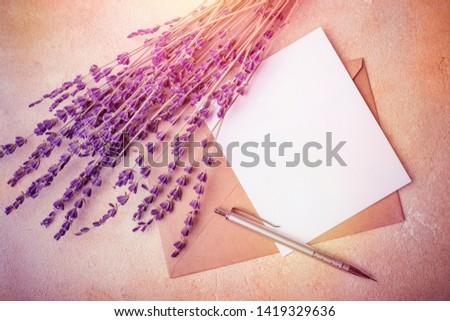 Blank paper with Kraft envelope and lavender flowers on a light background. View from above. Toning