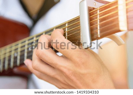 Musician playing finger style on acoustic guitar with capo