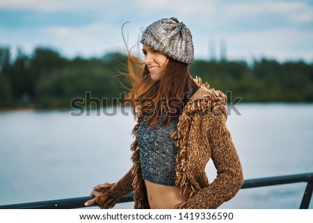 Beautiful young woman posing on the promenade at the river in the middle of the city
