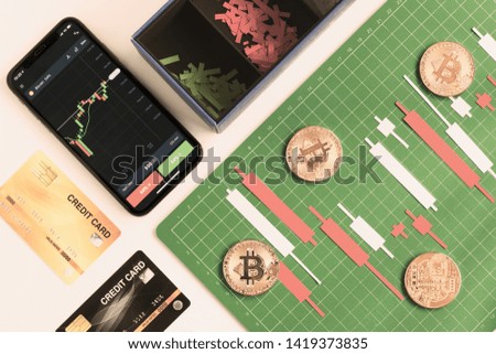 Top view, Candlestick chart make from color paper white and red on Green board with grid lines with smartphone credit card, investment, trading, stock, finance concept