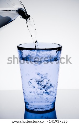 filling a blue glass with pure water and bubbles on table