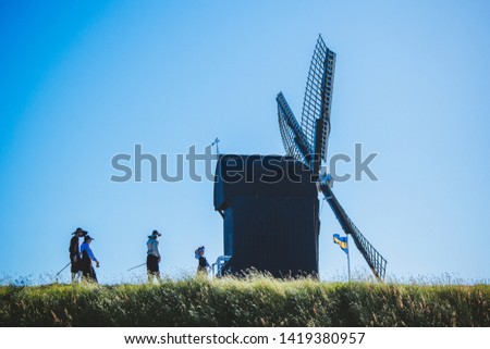 Wooden windmill, earthen wall of the fortress and people in historical costumes. Fortress and village Bourtange, Groningen, Netherlands.