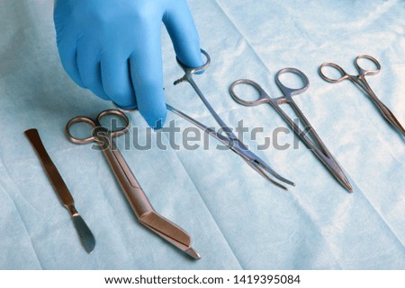 Detail shot of sterilized surgery instruments with a hand grabbing a tool ,