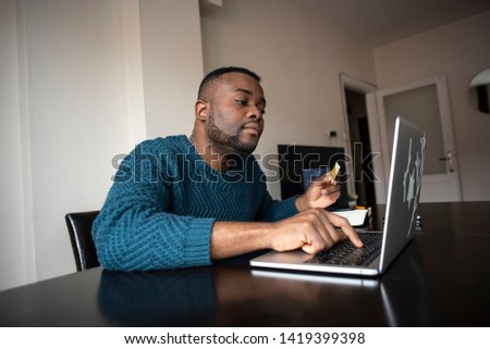 Black man makes purchases online using the card in the online store. Pays for utilities online. Buying goods with credit ore debit card. Man ordering a lunch from the house
