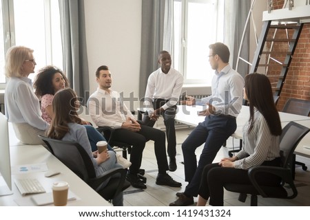 Multiethnic work group talk during casual office meeting, discuss business ideas sharing thoughts, smiling diverse colleagues or employees speak negotiating at informal briefing at workplace Royalty-Free Stock Photo #1419431324