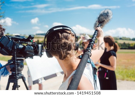 Woman holding microphone on a boom during video production capturing audio