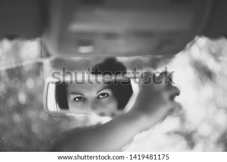 Black and white art picture of beautiful young woman face in the car rear view mirror. concept.