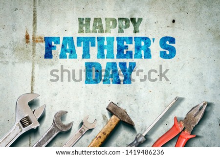 Happy father's day background. Inscription written on a concrete wall. Tools for repair. Adjustable wrench, hammer, screwdriver and various wrenches for repair. Congratulatory background.