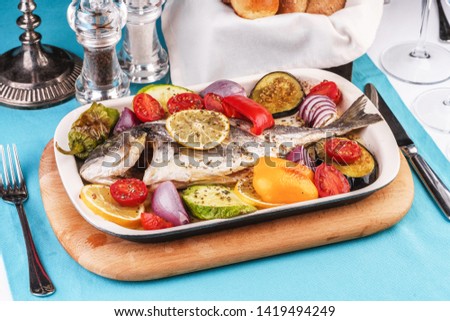 
Mediterranean dish, Georgian recipe. Baked river fish with lemon, vegetables, pepper and grilled tomatoes with spices.