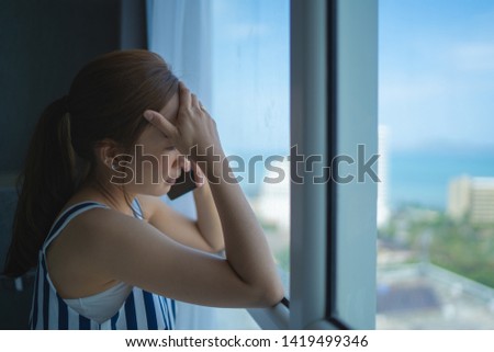 girl asian in sad emotional by use smartphone in room her by relaxing on vacation with serious talk beside windows Royalty-Free Stock Photo #1419499346