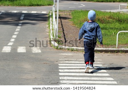 A child crosses the road at a pedestrian crossing