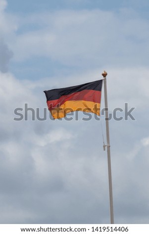 A German flag flying on a flag pole blowing in the wind 
