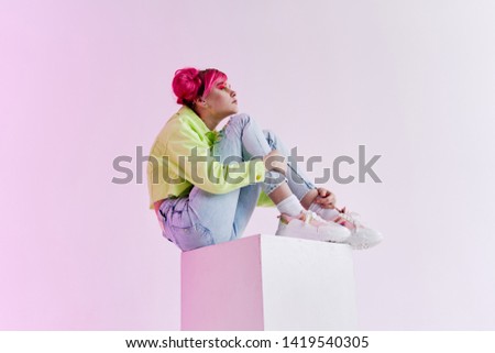 woman with pink hair sitting on a stone