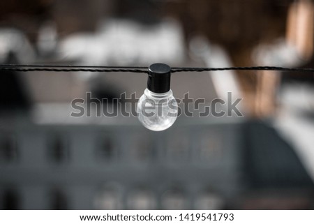 Glass bulb with black base on the background of houses. Light bulb up. The view from the top. Close up
