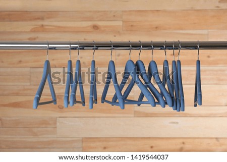 Metal rack with clothes hangers on wooden background