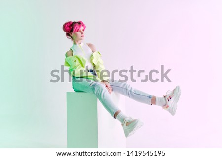 woman in a green jacket with pink hair sitting
