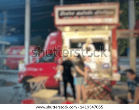 Blurred picture of customer waiting for order of food truck in the night scene at the street food market
