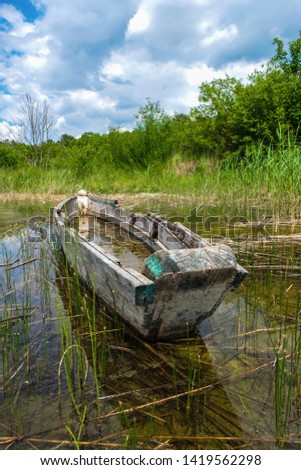 An old fishing boat in the shallow water of a pure lake Svityaz, Volyn, Ukraine. Shatsky national nature park. Vertical image.