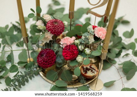 Festively decorated banquet table in the restaurant. Fresh flowers are golden candles and red chairs and garnet. expensively rich.