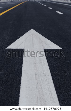 Asphalt road marked by straight arrow