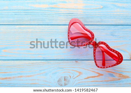 Modern heart shaped sunglasses on blue wooden table