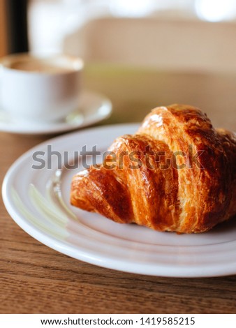 cup of cappuccino and tasty croissant on the wooden desktop. Flat lay style.