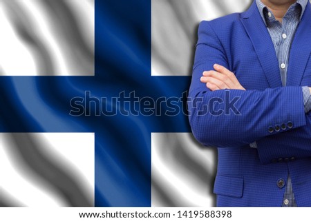 The concept of business, government, power. The elite of the country. Copy space or text. Man in blue suit close-up against the background of the developing flag of Finland